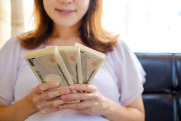大金を手に考える女性　妊婦　給付金