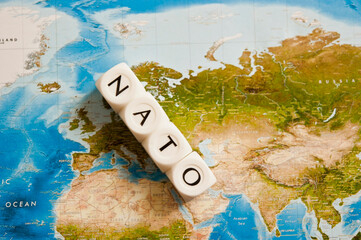 NATO spelled with dice on a world map, concept for the North Atlantic Treaty Organization expanding...