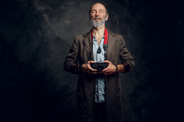 Studio shot of fashionable old man with photo camera dressed in casual attire.