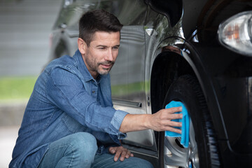 man giving a care on a tire with cloth