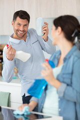 Obraz premium happy interracial marrieds cleaning in the kitchen together and smiling