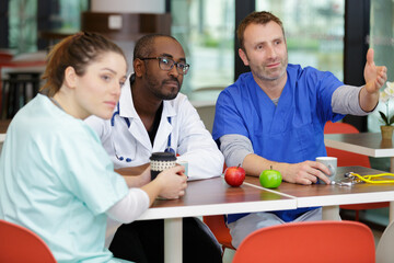 group of doctors in the cafeteria eating relaxing small talk