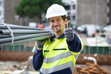construction worker on site holding pipe - obrazy, fototapety, plakaty