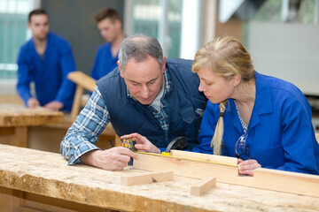 carpentry worker and apprentice measuring wood