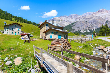 View of beautiful farm houses in Alpisella valley on sunny summer day, Alps Mountains, Italy