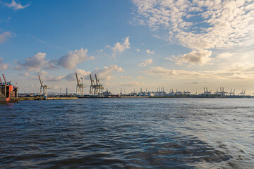 Fototapeta na wymiar Hamburg Harbor in the sunset light. Freight shipping cranes.
