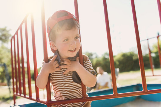 A Two-year-old Child Plays In A Fenced Playground Under The Supervision Of A Parent. Safe Games. Summer Outdoor Walks