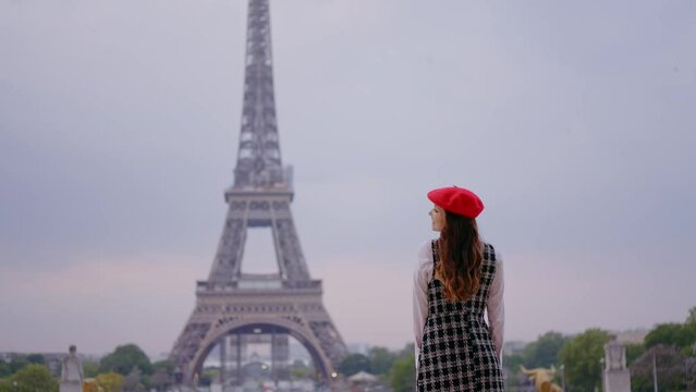 Cinematic footage of a young woman wearing fashionable clothes having fun in Paris at the eiffel tower park and  streets. Concept about european tourism and travels to the capital cities