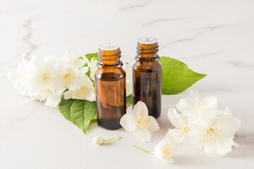 essential oil of jasmine flowers in two glass medical bottles against the background of flowers. spa, aromatherapy, relaxation.