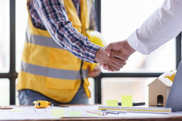 Architect contractor shaking hands with client after seal a deal to renovate building, engineer handshake partnership and contractor concept