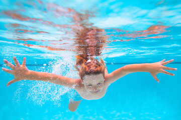 Child in pool in summer day. Young boy swim and dive underwater. Under water portrait in swim pool. Child boy diving into a swimming pool.