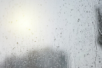 Abstract background with rain drops on window and blurred daylight.