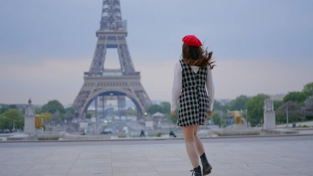 Cinematic footage of a young woman wearing fashionable clothes having fun in Paris at the eiffel tower park and  streets. Concept about european tourism and travels to the capital cities