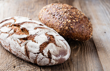 Gold rustic crusty loaves of bread and buns on wooden background. Still life captured from above top view, flat lay.