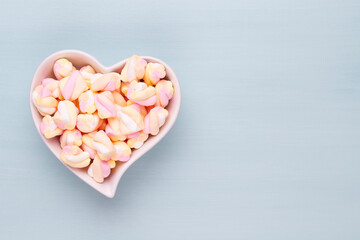 Marshmallows on blue background with copyspace. Flat lay or top view. Background or texture of colorful mini marshmallows.