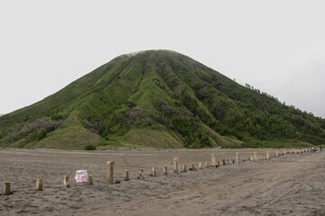 Scenery of Mount Batok "coconut shell", an inactive volcano with sea of sand and cloudy sky background in Bromo Tengger Semeru National Park.