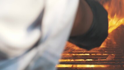 This stock video shows the chef cooking steaks on an open fire. This video will decorate your projects related to cooking meat on fire, the work of chefs, picnics, outdoor recreation.