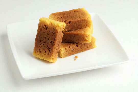 An Indian sweet originated from Mysore made from Ghee called mysore pak served on a white plate on a white background