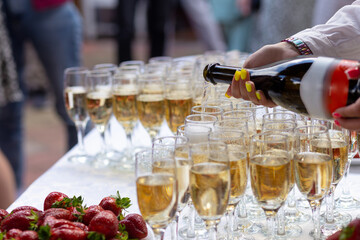 A banquet table with wine glasses and plates with strawberries.