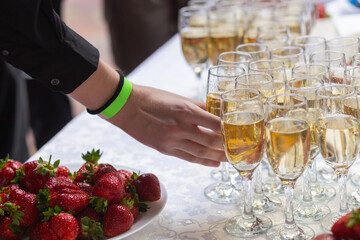 A banquet table with wine glasses and plates with strawberries.