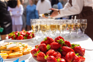 A banquet table with wine glasses and plates with snacks.