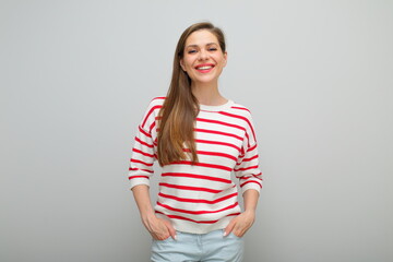 Obraz premium Smiling happy woman standing with hands in pockets, isolated female portrait, girl in white sweater with red stripes, young lady with long hair.