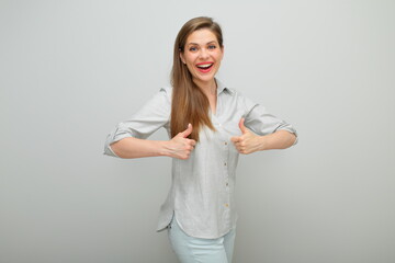 Smiling woman doing thumbs up with two hands, isolated female portrait, young lady dressed pants and gray shirt.