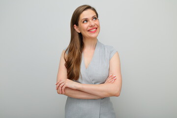 Obraz premium Young business woman standing with arms crossed looking up, , isolated female studio portrait, young business lady in gray dress.