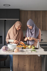 Two muslim women slicing, chopping and peeling vegetables at kitchen to prepare a salad.