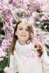 Portrait of a girl on a tree background with pink flowers.