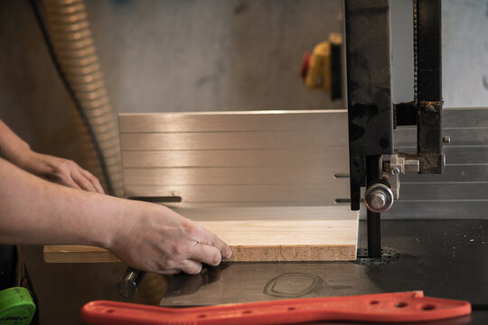 Unrecognizable joiner, professional man hands using panel sizing saw woodworking machine to cut wood board in workshop - Powered by Adobe