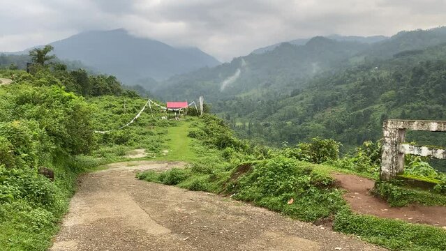 Tilt up shot of India Bhutan border at Jhalong , Dooars - West Bengal , India in a cloudy day with green mountains in the background.