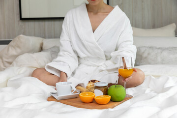 woman having breakfast on white bed