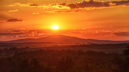 Vibrant sunset over wooded mountains in the countryside