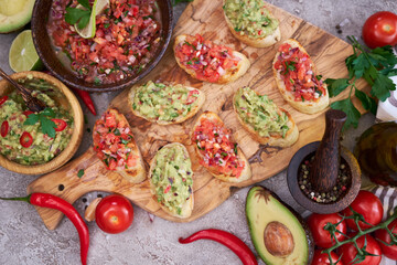 Fototapeta na wymiar tasty salsa and guacamole bruschetta snacks at domestic kitchen on wooden cutting board