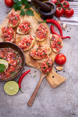 tasty salsa bruschetta snacks at domestic kitchen on wooden cutting board