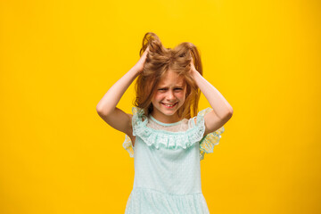 A children with disheveled ruffled hair grabbed her head