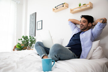 African American using computer laptop on the bed with happiness while watching favorite movies. Web surfing information on computer in bedroom