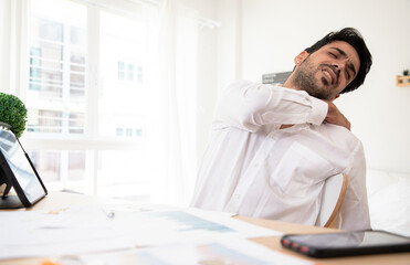 Tired American office worker on chair suffer from sitting long in incorrect posture, Handsome employee have back pain or spinal spasm working at home