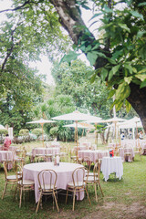 Flower arrangement for summer wedding, made of roses and green branches on a dinner table in the restaurant. , glass and plates in the restaurant outside on a windy day with film grain effect