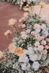 Flower arrangement for summer wedding, made of roses and green branches on a dinner table in the restaurant. , glass and plates in the restaurant outside on a windy day with film grain effect