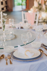 Flower arrangement for summer wedding, made of roses and green branches on a dinner table in the restaurant. , glass and plates in the restaurant outside on a windy day with film grain effect