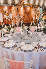 Flower arrangement for summer wedding, made of roses and green branches on a dinner table in the restaurant. , glass and plates in the restaurant outside on a windy day with film grain effect