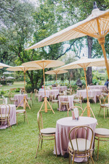 Flower arrangement for summer wedding, made of roses and green branches on a dinner table in the restaurant. , glass and plates in the restaurant outside on a windy day with film grain effect