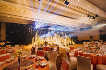 Flower arrangement for summer wedding, made of roses and green branches on a dinner table in the restaurant. , glass and plates in the restaurant outside on a windy day with film grain effect