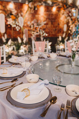 Flower arrangement for summer wedding, made of roses and green branches on a dinner table in the restaurant. , glass and plates in the restaurant outside on a windy day with film grain effect