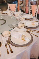 Flower arrangement for summer wedding, made of roses and green branches on a dinner table in the restaurant. , glass and plates in the restaurant outside on a windy day with film grain effect