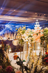 Flower arrangement for summer wedding, made of roses and green branches on a dinner table in the restaurant. , glass and plates in the restaurant outside on a windy day with film grain effect
