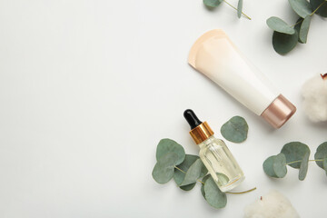 Organic skin care products on white background with fresh green eucalyptus leaves.