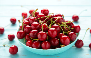 Fresh sweet cherries bowl on blue background. Top view.
